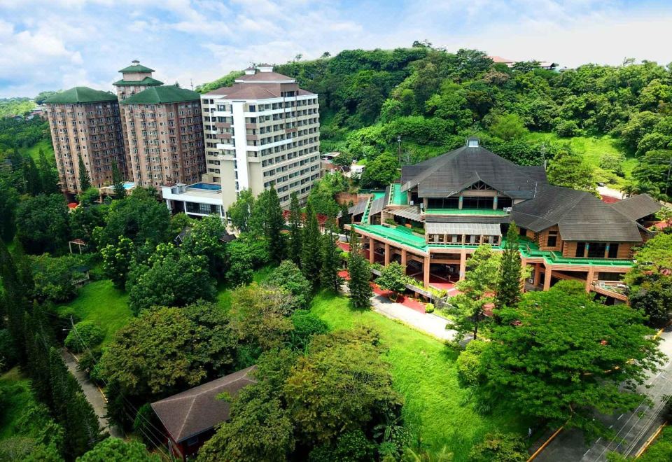 aerial view of a large hotel surrounded by trees and mountains , with a swimming pool in the foreground at Canyon Woods Resort Club