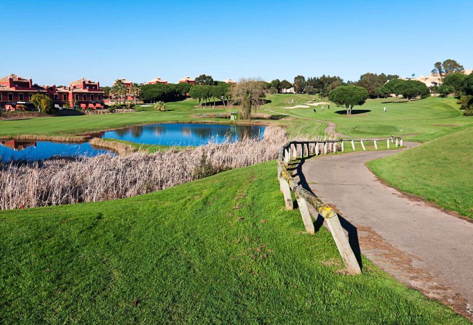 a beautiful golf course with a pond in the middle , surrounded by green grass and trees at DoubleTree by Hilton Islantilla Beach Golf Resort