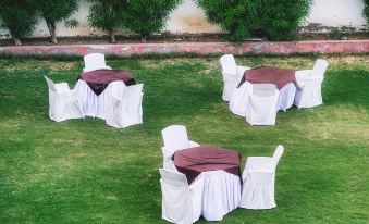 a group of white chairs and tables are set up on a grassy area with trees in the background at Hotel Empire