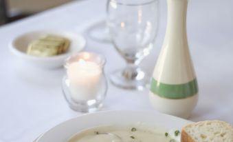 a dining table with a bowl of soup , a plate of food , and a candle at Sunset Hill House