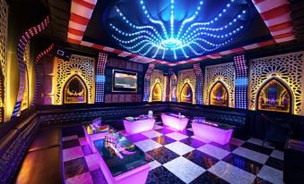 a luxurious nightclub with an ornate ceiling , purple lights , and a chess - like checkered floor , as well as several tables and chairs at Muong Thanh Grand Hoang Mai - Nghe An