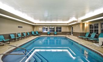 a large swimming pool with blue water and lounge chairs in a hotel lobby setting at Residence Inn Dayton Beavercreek