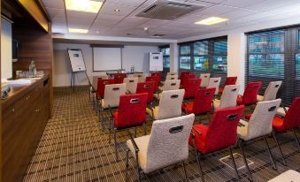 a conference room with rows of chairs arranged in a semicircle , and a projector screen on the wall at Holiday Inn Express East Midlands Airport
