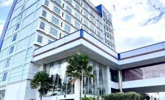 a large white building with a blue and white color scheme , situated in a city setting at Grand Asrilia Hotel