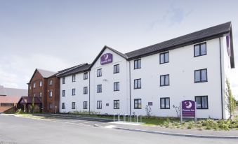a large white building with purple signage and black windows , located in a parking lot at Oswestry