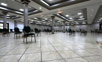 a large , empty conference room with rows of green chairs and white columns , under high ceiling with recessed lighting at Costa Bahia Hotel, Convention Center and Casino