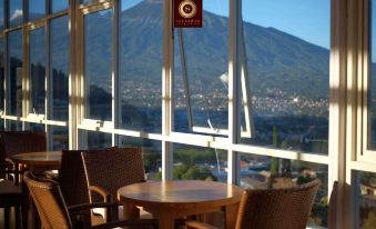 a room with a large window overlooking a mountain and a table with two chairs at Seulawah Grand View