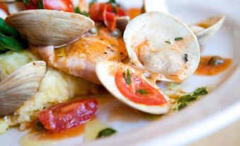 a close - up of a plate filled with a variety of seafood , including shrimp , clams , and mussels , on a white plate at Mountain Lake Lodge