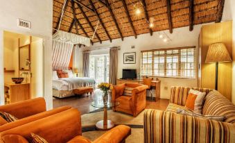 a cozy living room with orange furniture , a bed , and a tv . also a dining table in the room at Summerhill Guest Estate