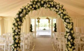 a wedding ceremony setup under a white canopy with flowers and tables in the background at Rettendon Lodge