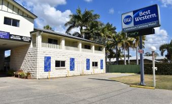 "a white building with blue doors and windows , a sign reading "" best western gulf coast "", and palm trees in the background" at Best Western Caboolture Gateway Motel
