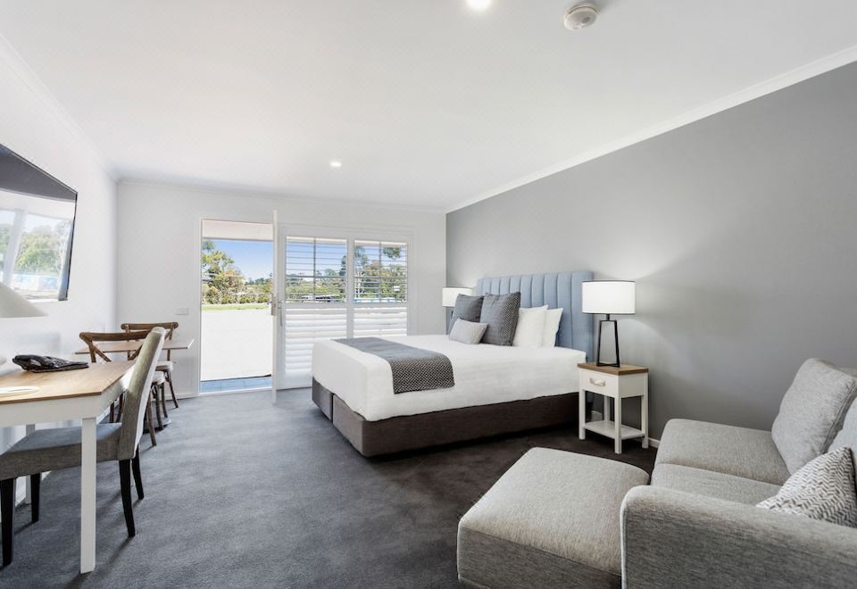 a large bed with a white and gray headboard is in the center of a room at Sanctuary Inn on Westernport