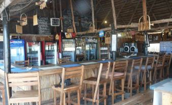 a wooden bar with several stools and chairs , as well as a refrigerator filled with drinks at White Sands