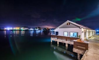 a small white house with a balcony and wooden railing is situated on the shore of a calm lake at Baan Tah on the Sea