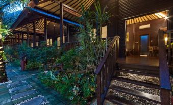 a wooden house with a stone staircase leading up to the front door , surrounded by lush greenery at Coconut Boutique Resort