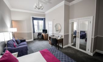 a spacious bedroom with a king - sized bed , a flat - screen tv , and a door leading to a balcony at Kincaid House Hotel