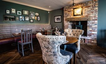 a cozy corner of a restaurant with wooden furniture , brick walls , and framed pictures on the wall at The Saracens Head