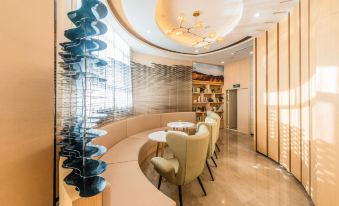 a modern , well - lit lobby with curved seating and a unique sculpture at the center of the room at Atour Hotel