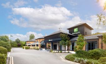 a holiday inn hotel with its large , modern building and green signage under a cloudy sky at Holiday Inn Gloucester - Cheltenham