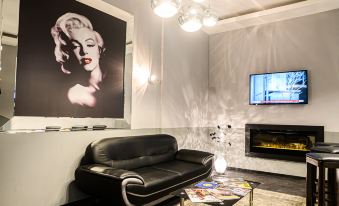 a living room with a black leather couch , a fireplace , and a painting of marilyn monroe on the wall at Hotel Luna