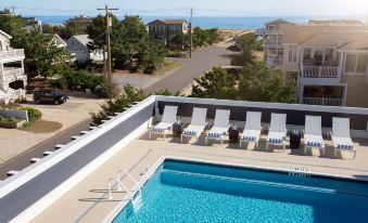 a rooftop pool surrounded by white lounge chairs , with a view of the ocean in the background at Fenwick Shores, Tapestry Collection by Hilton