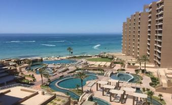 a large , modern resort with multiple pools and water slides is shown overlooking the ocean at Las Palomas Beach & Golf Resort