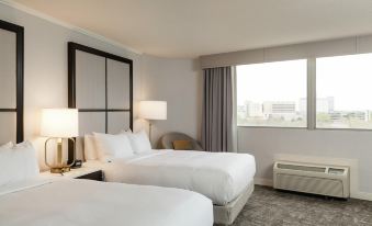 a modern hotel room with two beds , white bedding , and a window offering a view of the city at Hilton Chicago/Oak Lawn