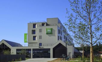 "a modern building with a green and white sign that reads "" rih "" is surrounded by trees" at Ibis Styles Paris Romainville