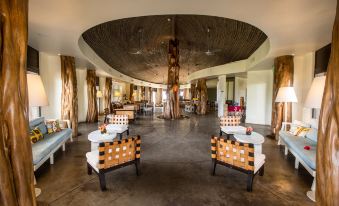 a large , modern room with wooden furniture and a tree trunk - like structure in the center at Nayara Hangaroa