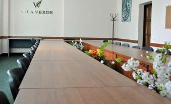 a long wooden table with a vase of flowers in the center and two chairs at the end at Vila Verde