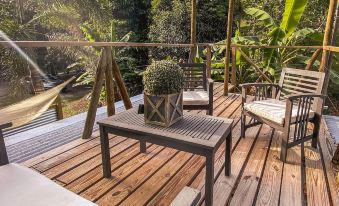 a wooden deck with a table and chairs , a potted plant , and a swing hanging from the trees at Hacienda Tres Casitas