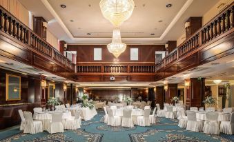 a large , elegant banquet hall with multiple tables set for a formal event , including white tablecloths and chairs at Hotel President Solin