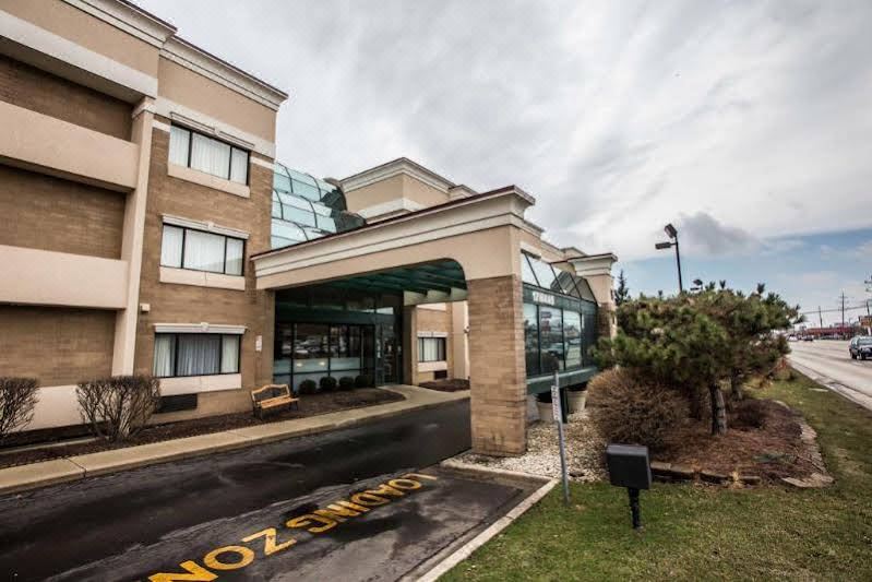 a large , modern hotel with a glass entrance and a grassy area in front of it at Comfort Suites Oakbrook Terrace Near Oakbrook Center