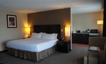 a large bed with white linens is in a room with two lamps and a kitchenette at Holiday Inn Portsmouth Downtown