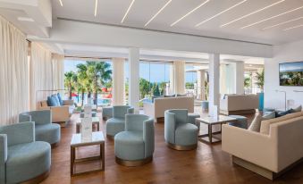 a modern lounge area with blue and white chairs , tables , and a pool in the background at Cascade Wellness Resort