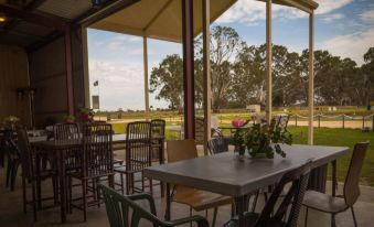 a covered outdoor dining area with tables and chairs , surrounded by trees and a beautiful view of the ocean at Coonawarra Bush Holiday Park