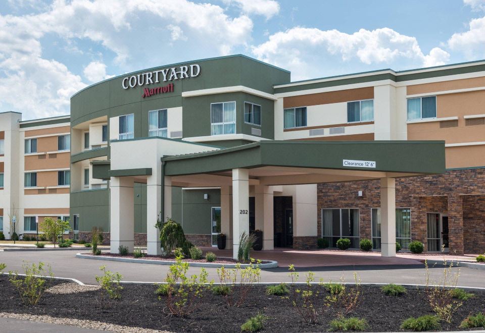 a courtyard by marriott hotel with a green and white color scheme , situated on a busy street at Courtyard Elmira Horseheads