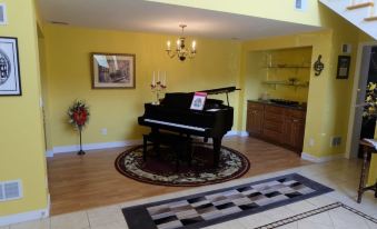 a living room with a piano , rug , and cabinet , surrounded by framed pictures on the wall at Seams Like Home B&B