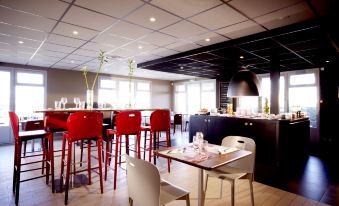 a modern restaurant with red chairs and tables , a white dining table , and large windows at Campanile Villejust - ZA Courtaboeuf