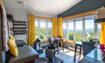 a living room with a couch , chairs , and dining table in front of large windows at Hotel & Spa Mont Gabriel