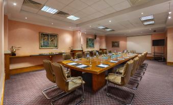 a large conference room with a long wooden table and multiple chairs arranged for a meeting at GrandResort by Leonardo Hotels