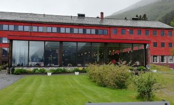 a red building with large windows is surrounded by greenery and has a grassy area in front at Stalheim Hotel