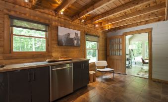 a wooden kitchen with a dining area , featuring stainless steel appliances and a large picture on the wall at Chatfield Hollow Inn