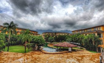 a large building with a pool and umbrellas is surrounded by trees and mountains under a cloudy sky at Discover Resorts