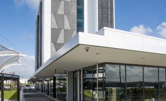 a modern building with a white and gray facade , located in a city with a train station in the background at Quest Highbrook