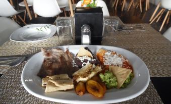 a dining table with a large white plate filled with various food items , including meat , vegetables , and sauces at Hotel Imperial