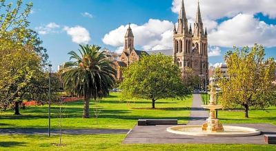 a large cathedral is seen in the background of a park with palm trees and a fountain at Oval Hotel at Adelaide Oval, an EVT hotel