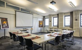 a conference room set up for a meeting , with chairs arranged in rows and a projector on the wall at ibis Lyon Sud Oullins