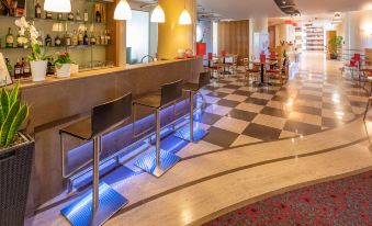a modern , well - lit bar with a checkered floor and various bottles of liquor on the counter at Ibis Firenze Nord Aeroporto