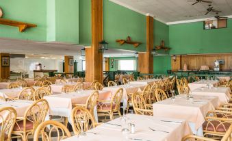 a large dining room with green walls and wooden chairs is filled with tables and chairs at Blue Sea Costa Bastian